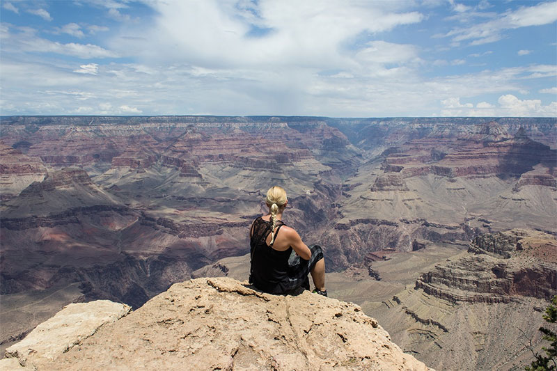 Woman sitting on mountain overlooking the Grand Canyon