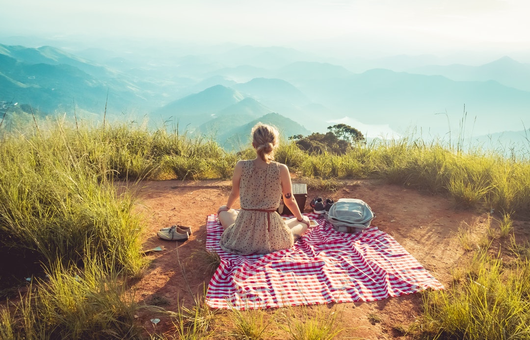 woman wearing gray sleeveless dress sitting on the picnic mat