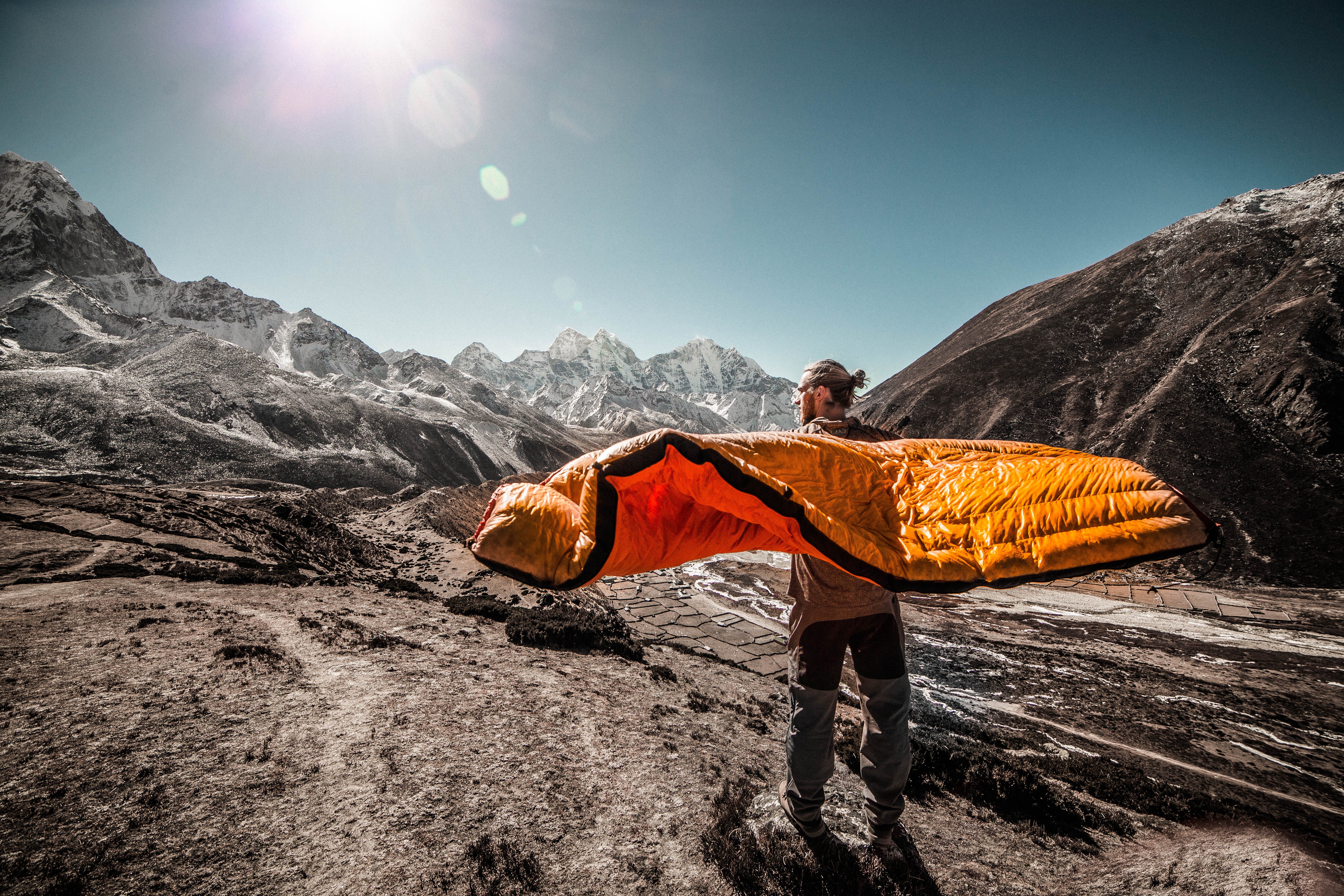 Man Standing on field between cliffs holding the best sleeping bag