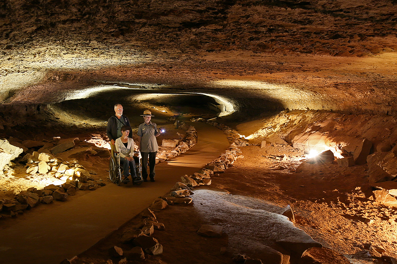 Accessible Mammoth cave tour with park ranger inside the lit up orange, rock covered cave.
